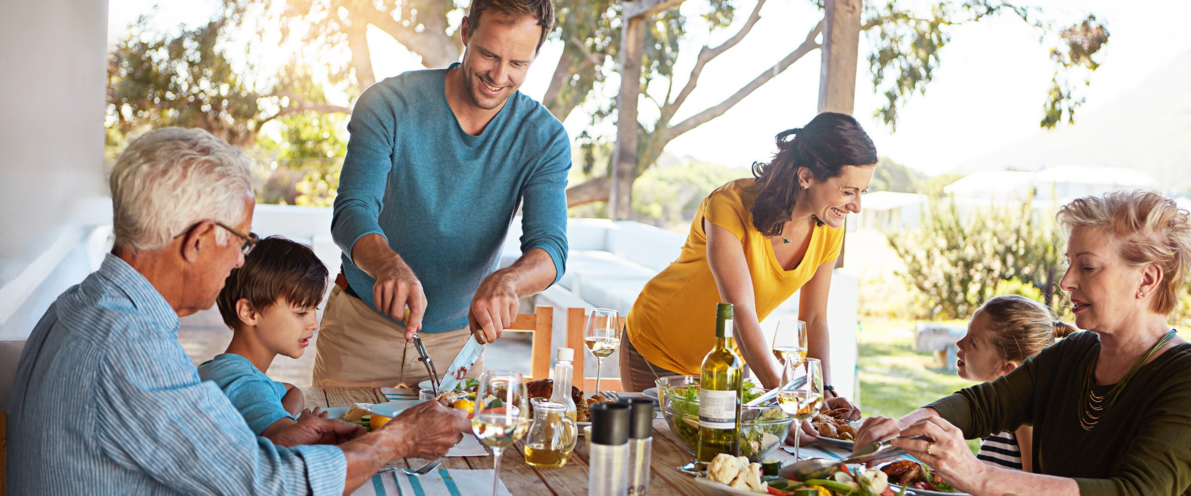 Photo of inter-generational family having dinner outdoors.