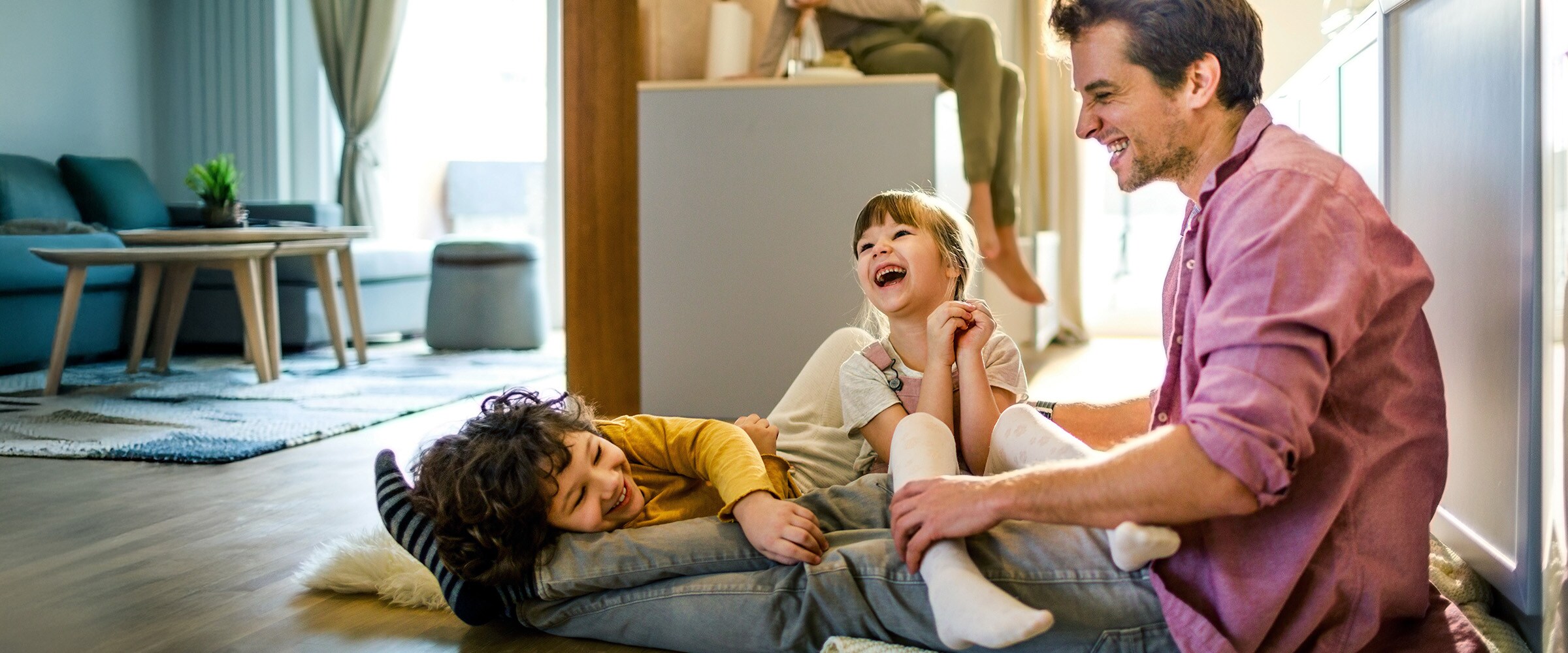 Photo of family laughing together on the living room floor.