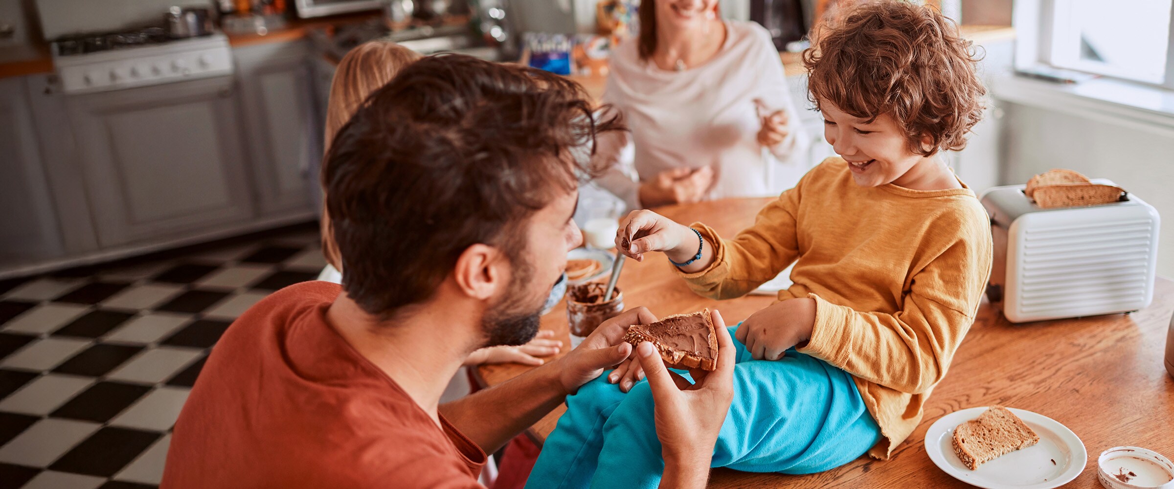 Photo of dad spreading Nutella on toast with child.