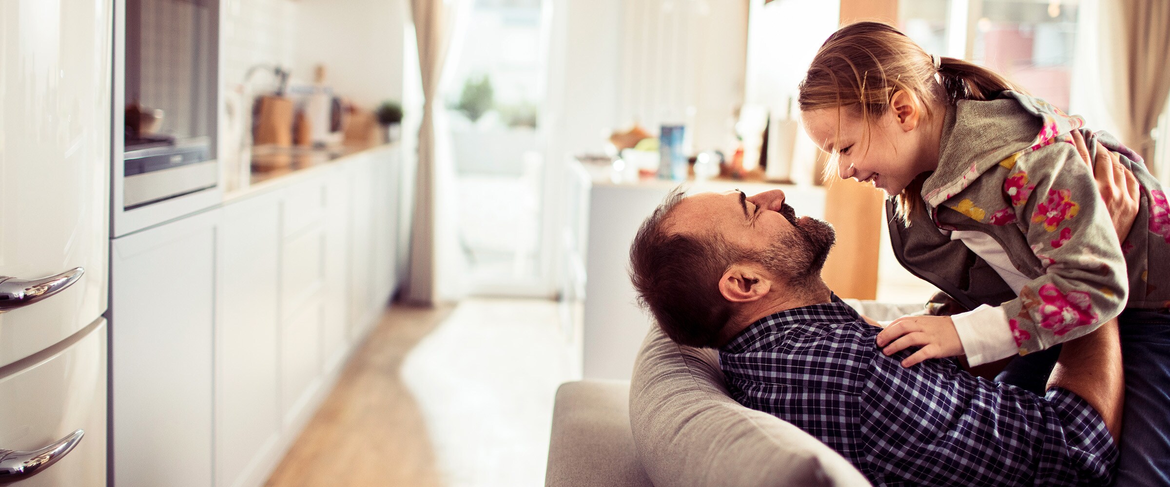 Photo of father holding up young son on a couch.