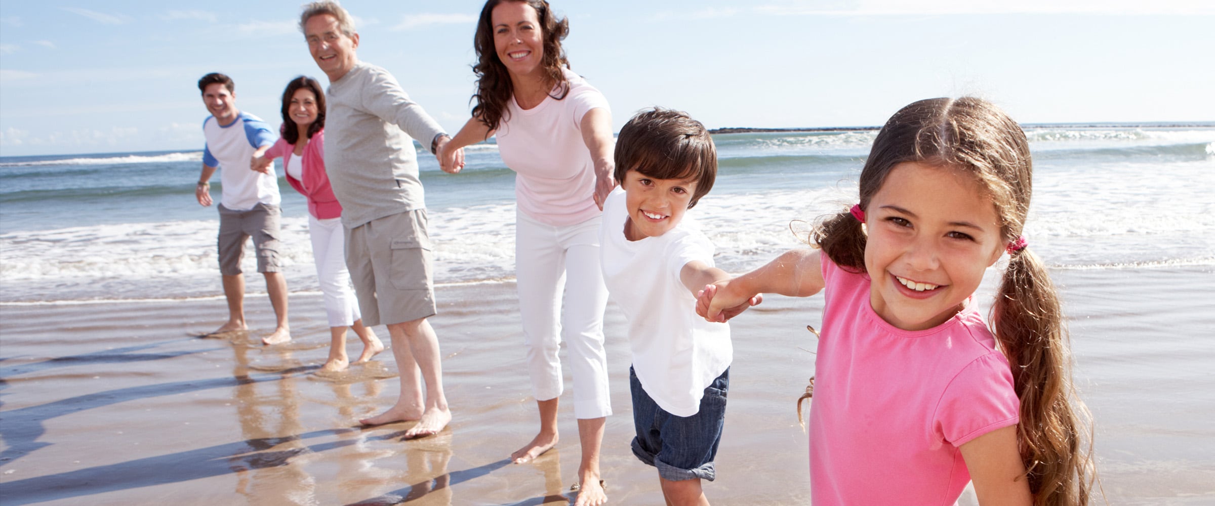 Photo of a family holding hands on a beach shore.