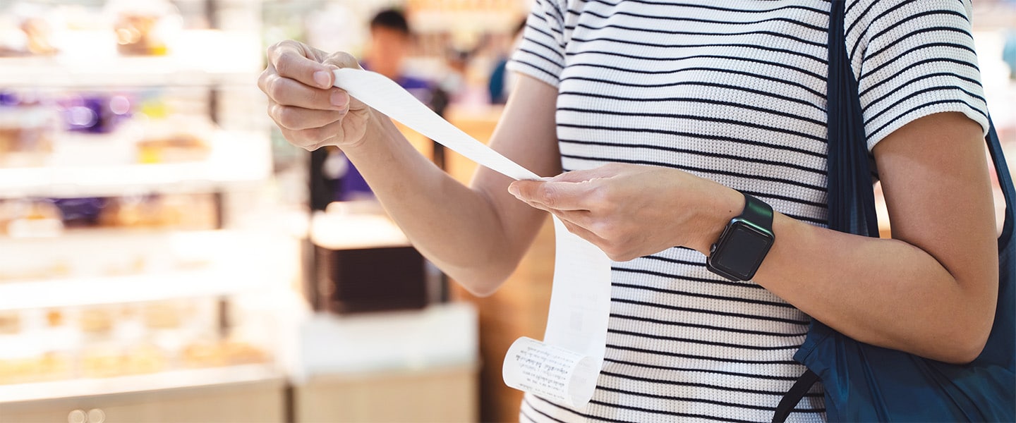 Close up photo of woman looking at her grocery receipt.