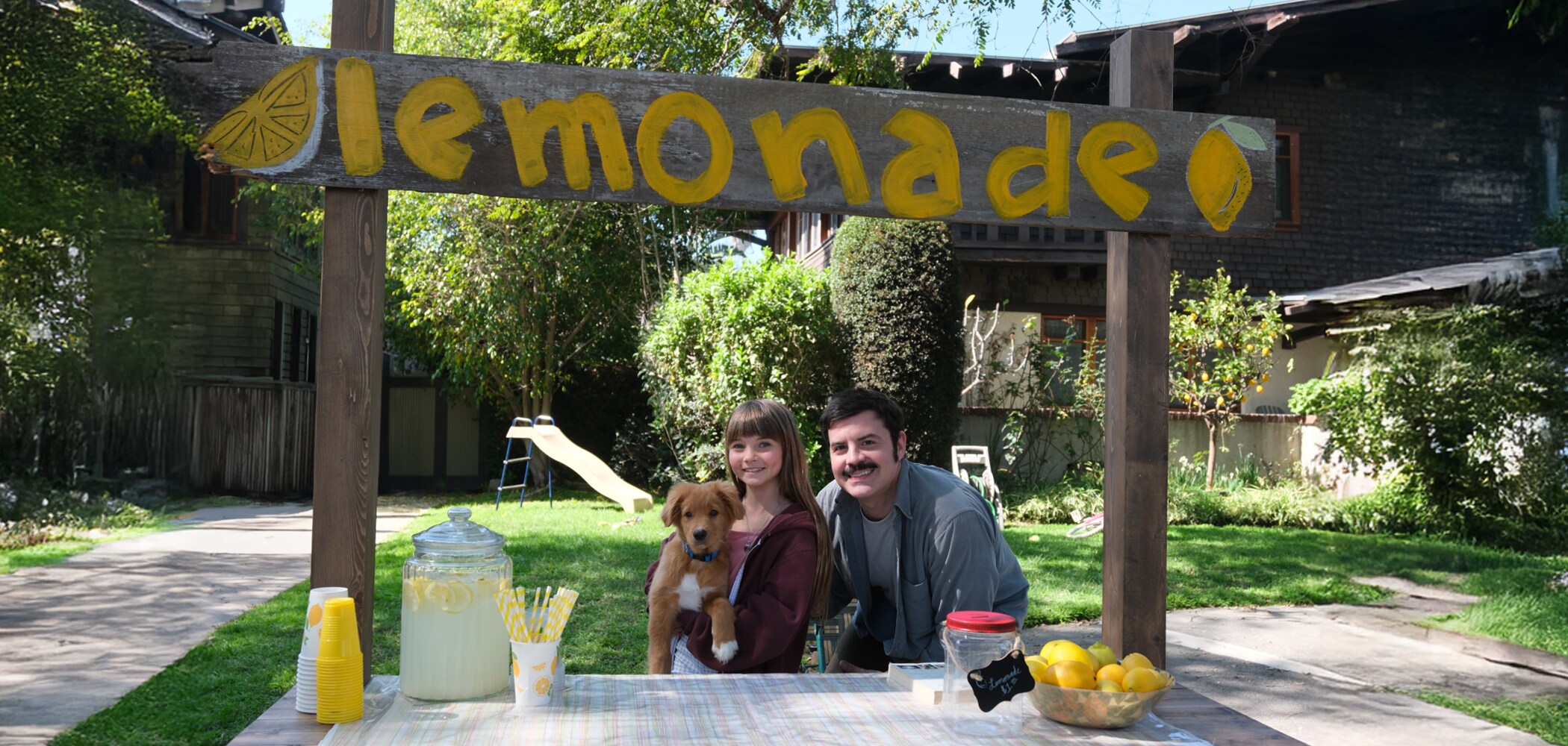 Photo of girla dad and their dog under the lemonade sign board