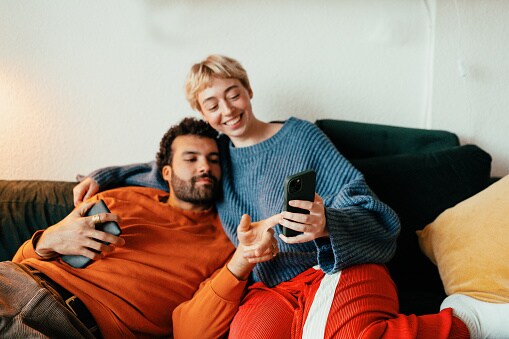 Couple relaxing together on couch browsing on phone