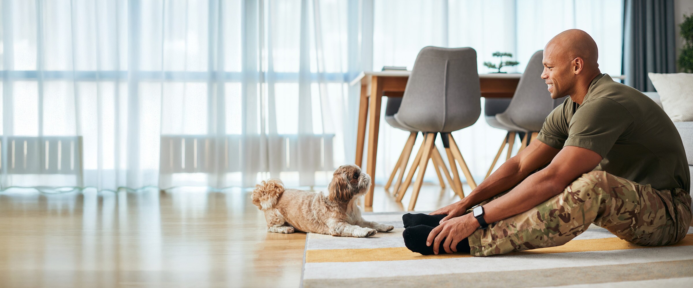 Photo of man in camos exercising in front of small cute dog.
