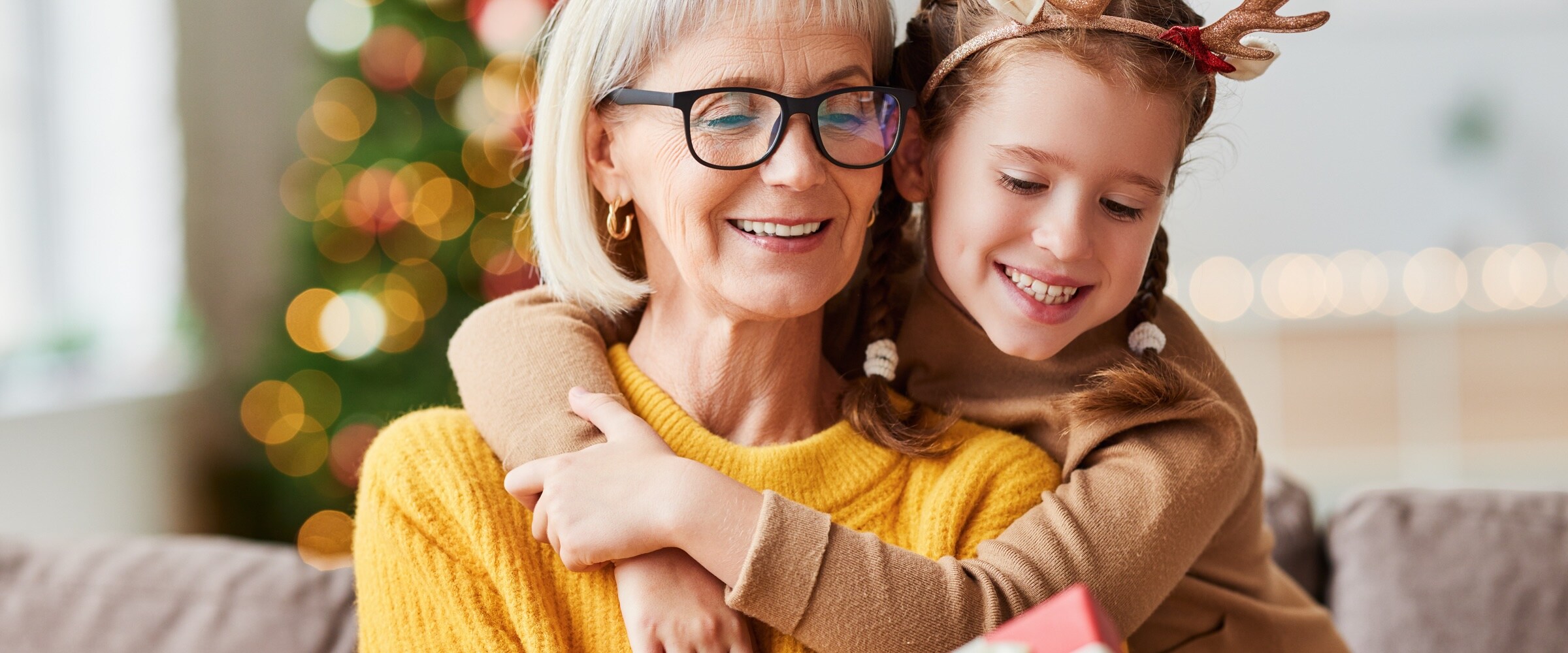 Photo of older woman with child wearing antlers hugging her.