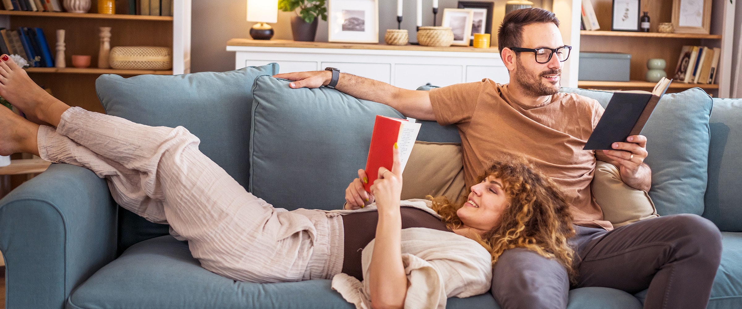 Photo of a young couple reading books on the couch.