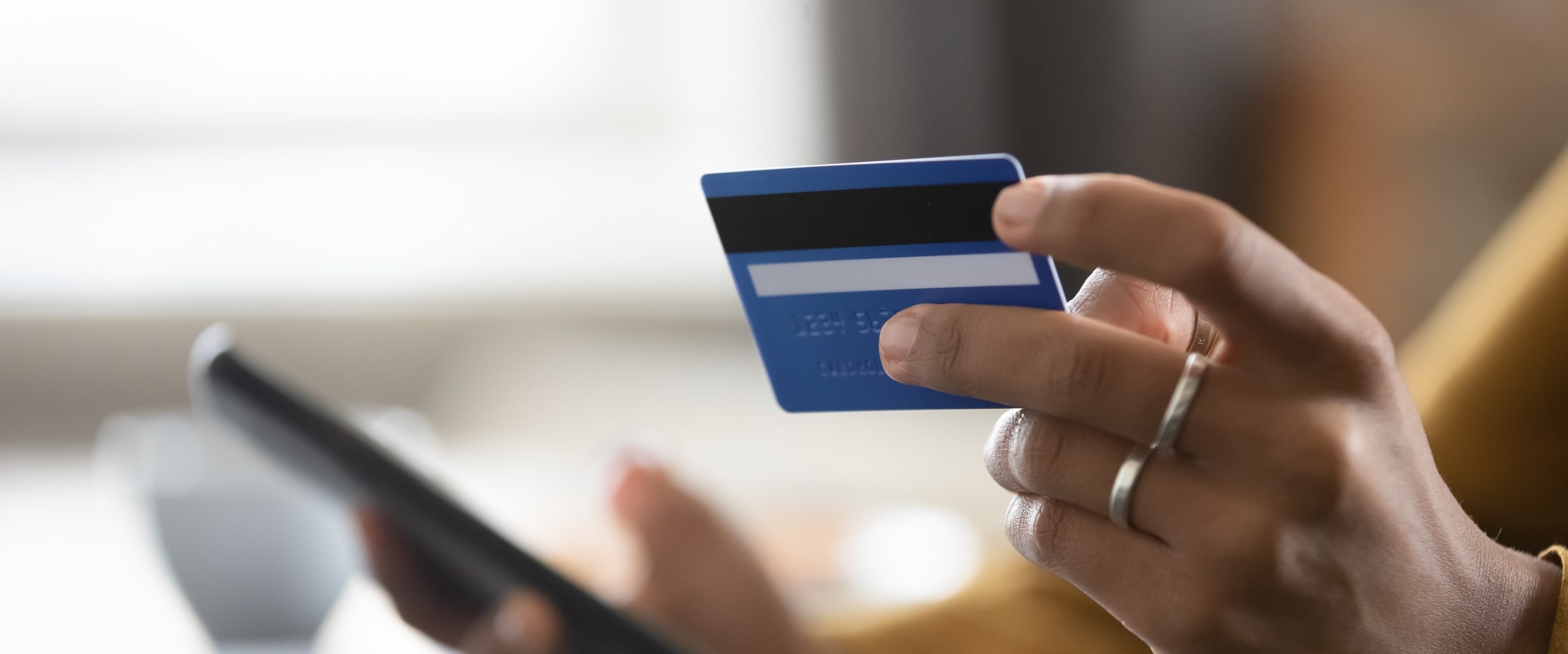 Photo of hand holding a bank card and holding phone in other hand.