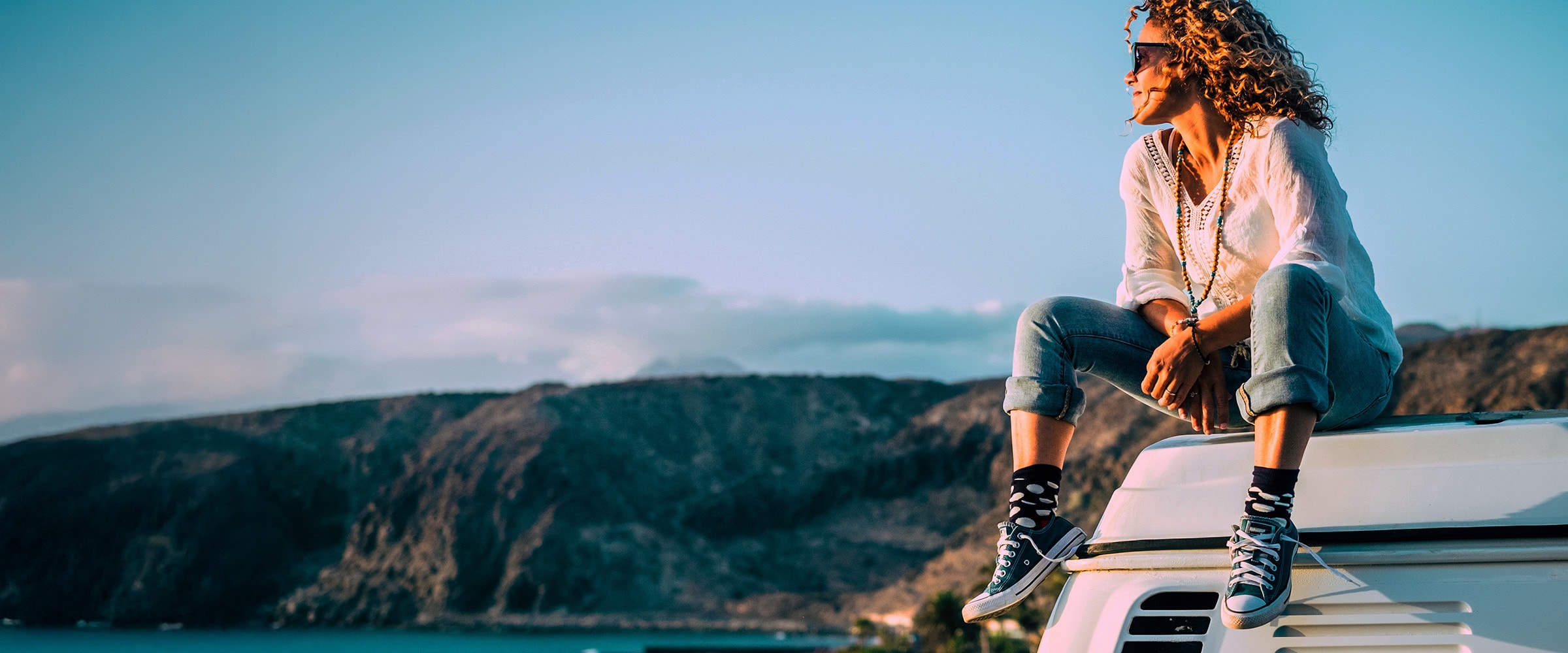 Photo of woman sitting on top of car.