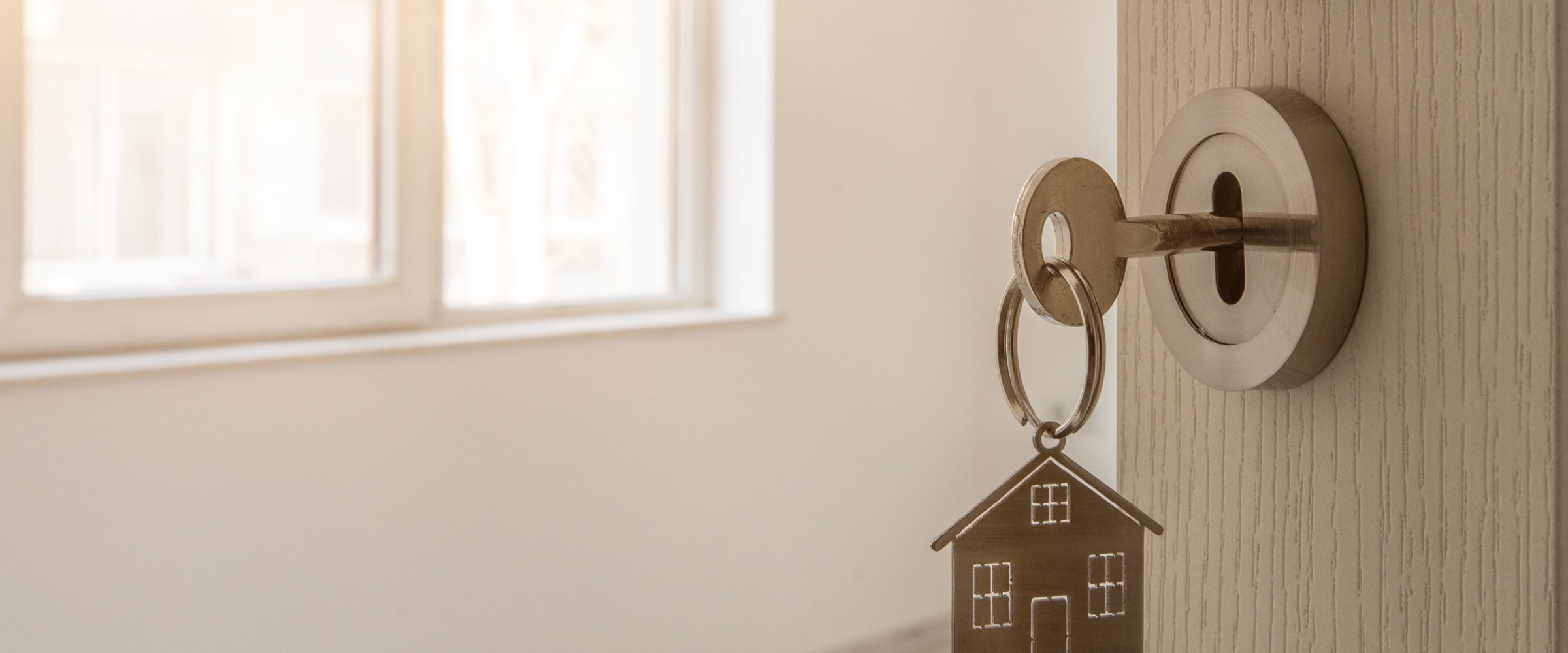 Photo of a key in the lock of an open door to a home.