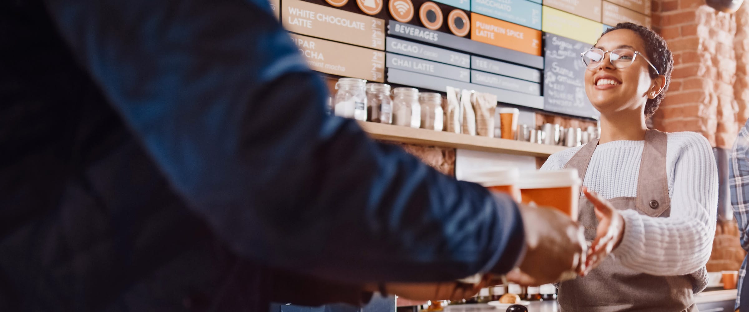 Photo of barista handing over a tray of coffee cups.