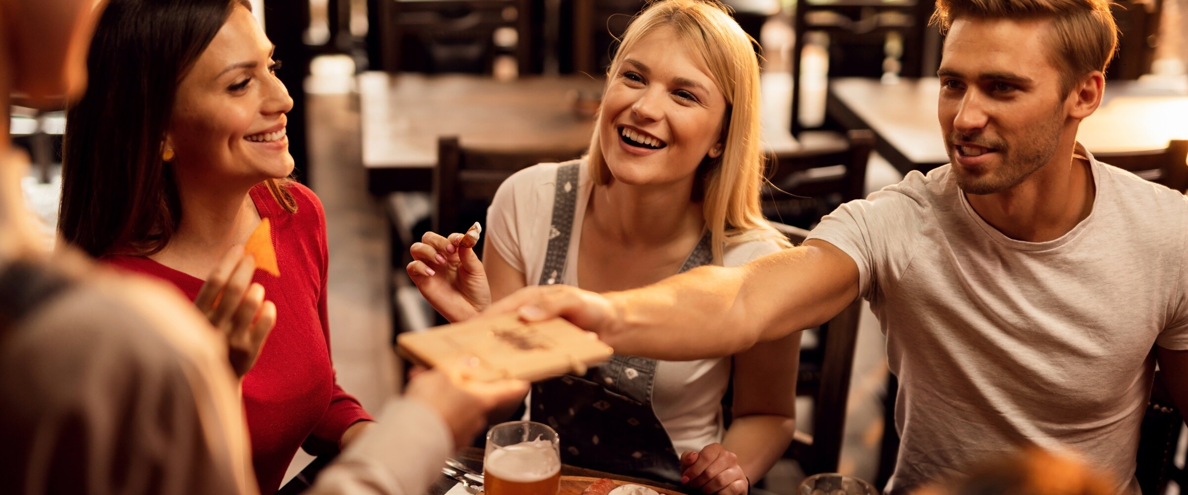 Photo of group at a restaurant table. One member pulls out their credit card.