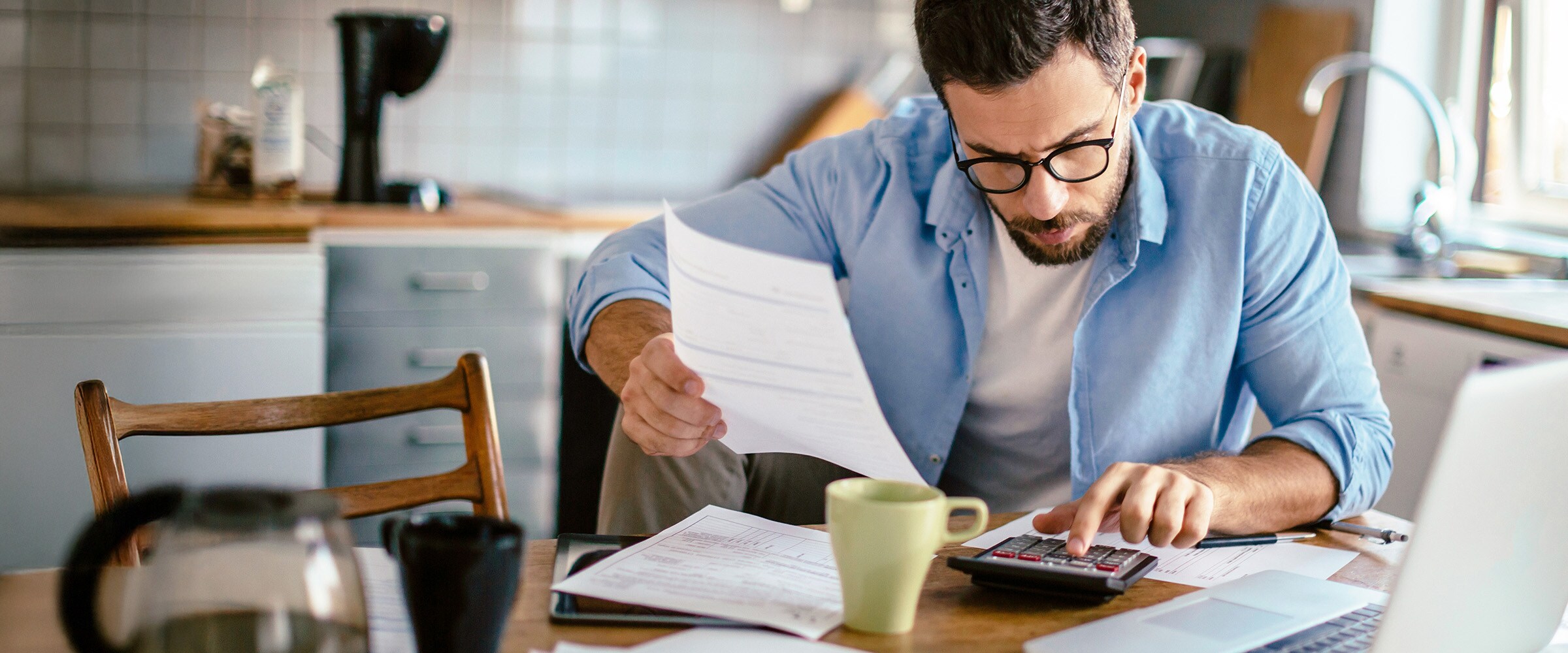 Photo of young man at desk going through his tax paperwork.