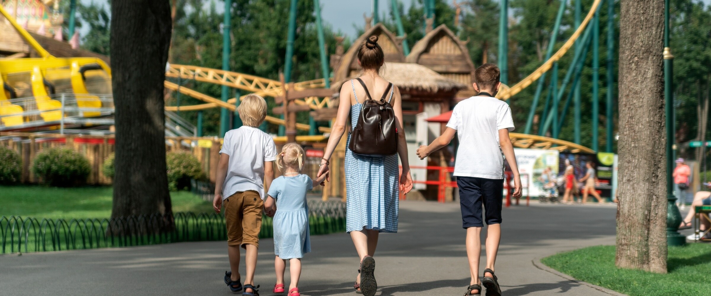 Photo of mom and three kids walking into an amusement park.