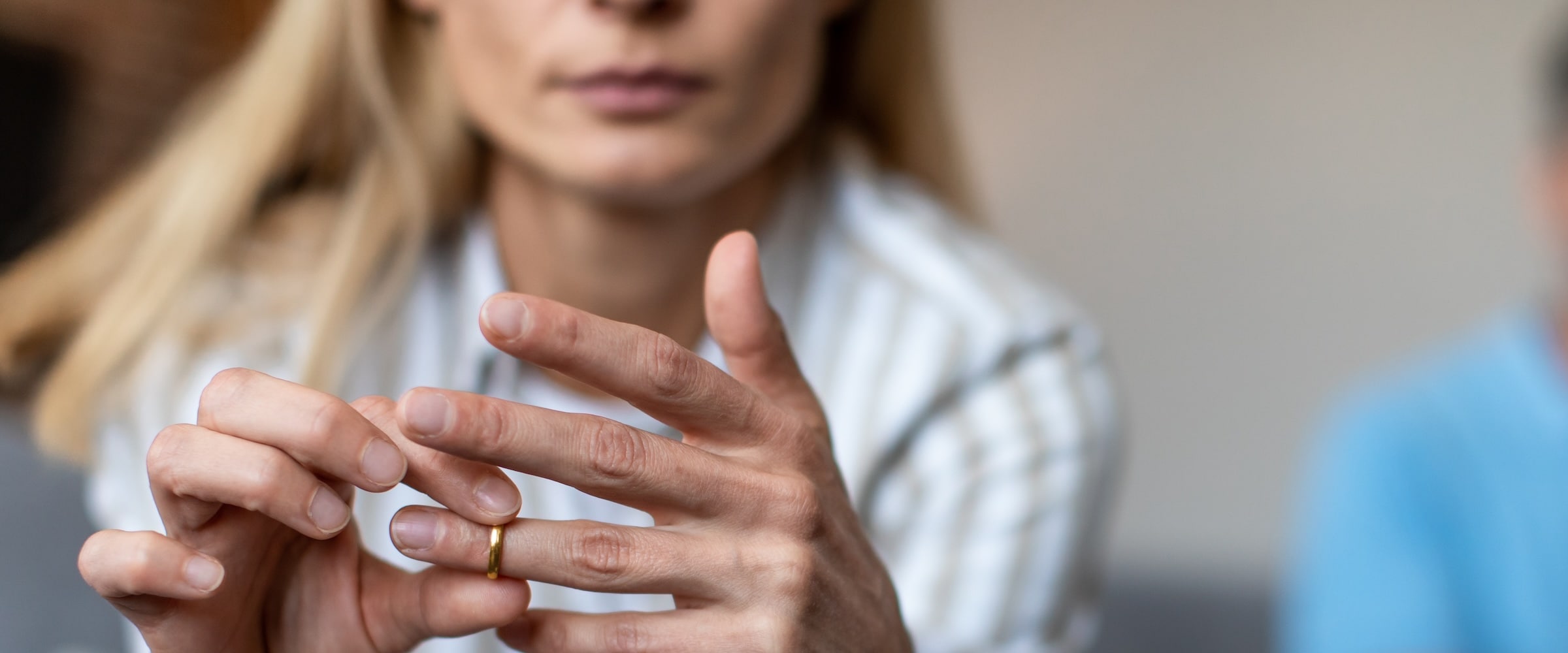 Photo of woman sliding wedding ring on her finger.