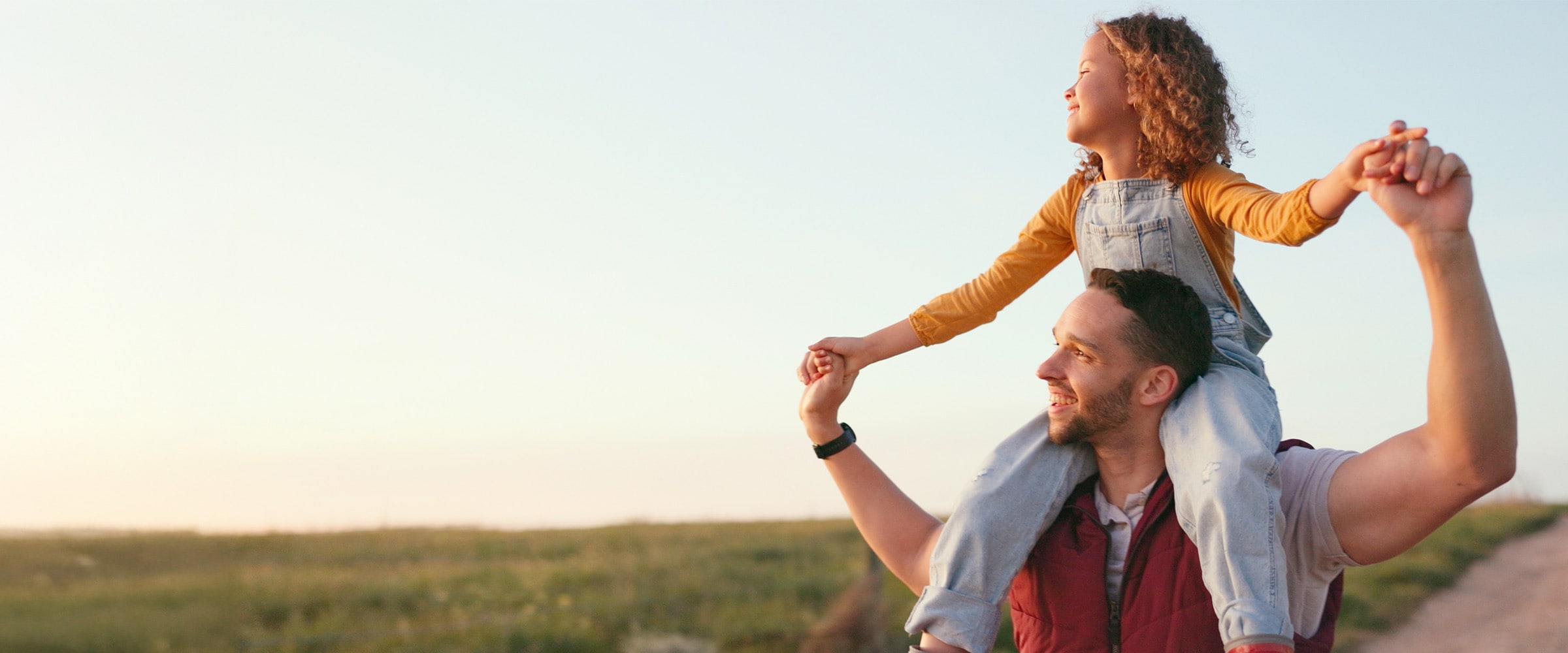 Photo of man holding his daughter over his shoulders.