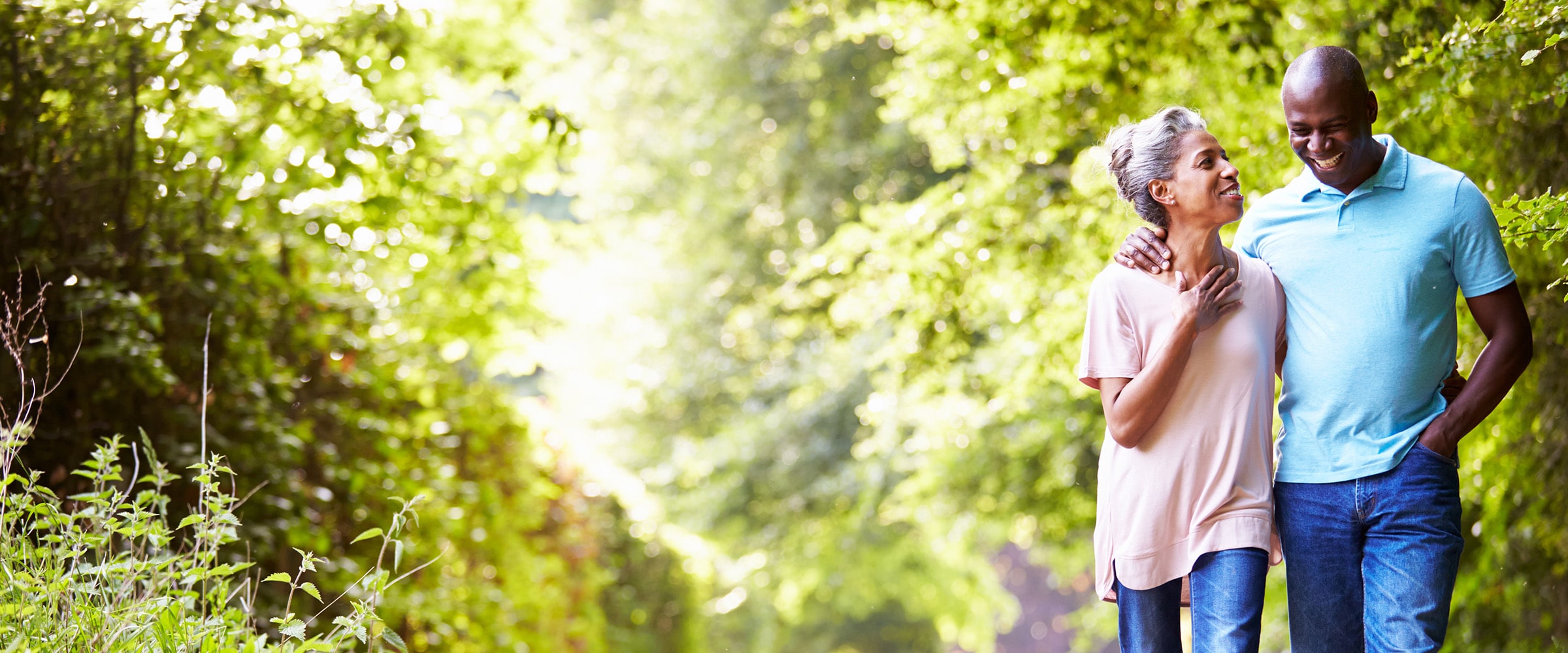 Photo of older couple walking on a path in the woods.
