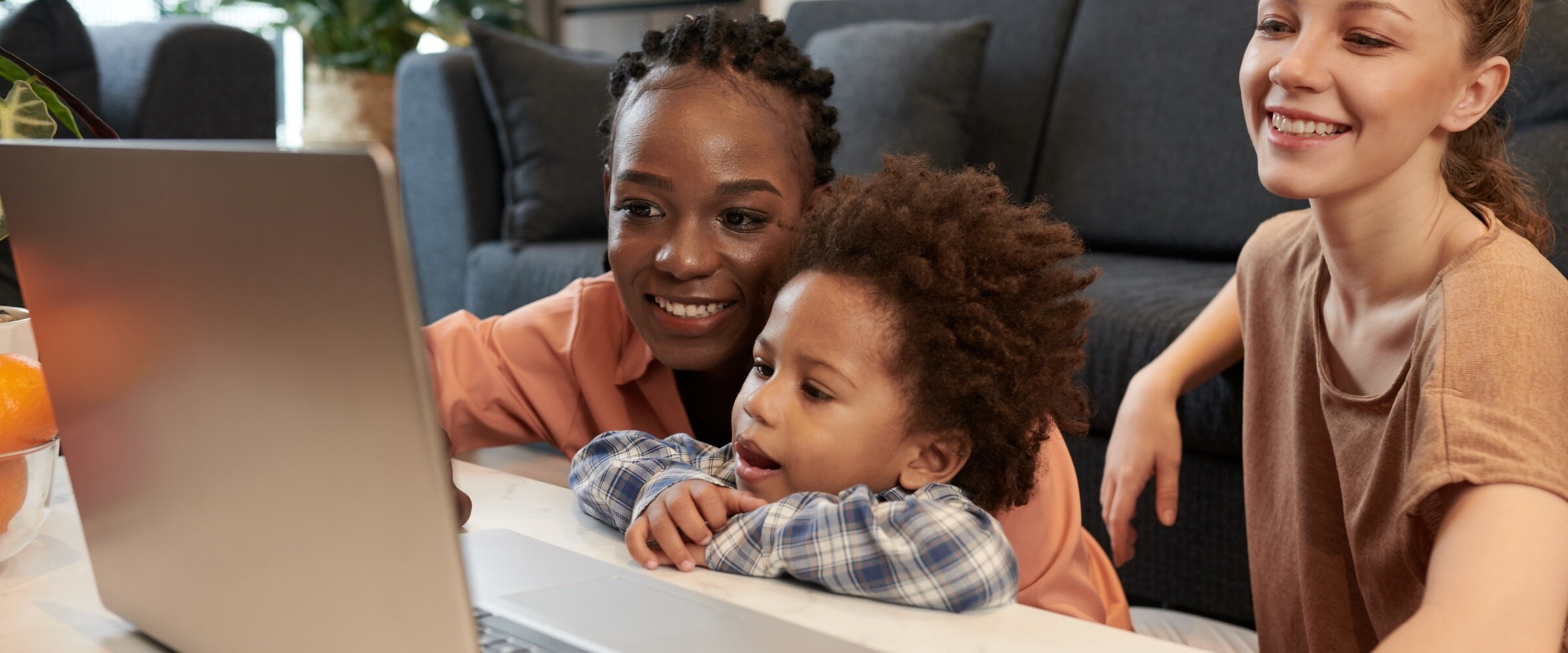 Photo of female couple with small child looking at a computer laptop.