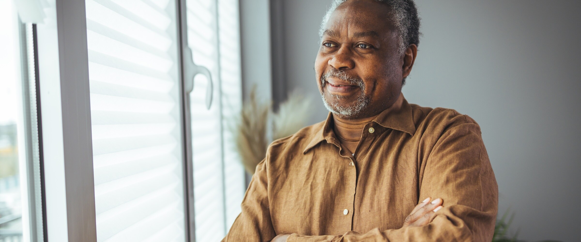 Photo of elderly African American looking out a house window.