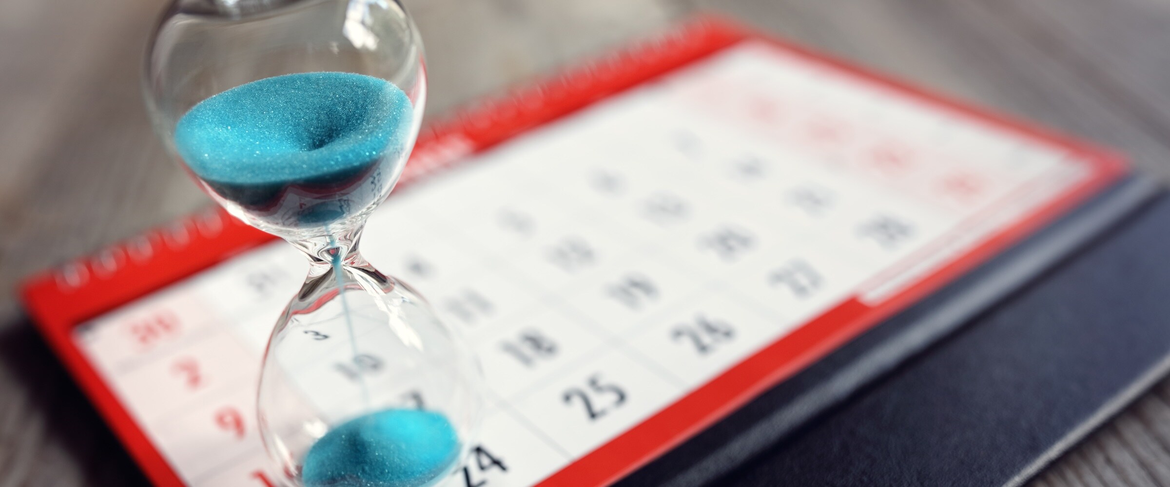 Photo of hourglass on top of a calendar.