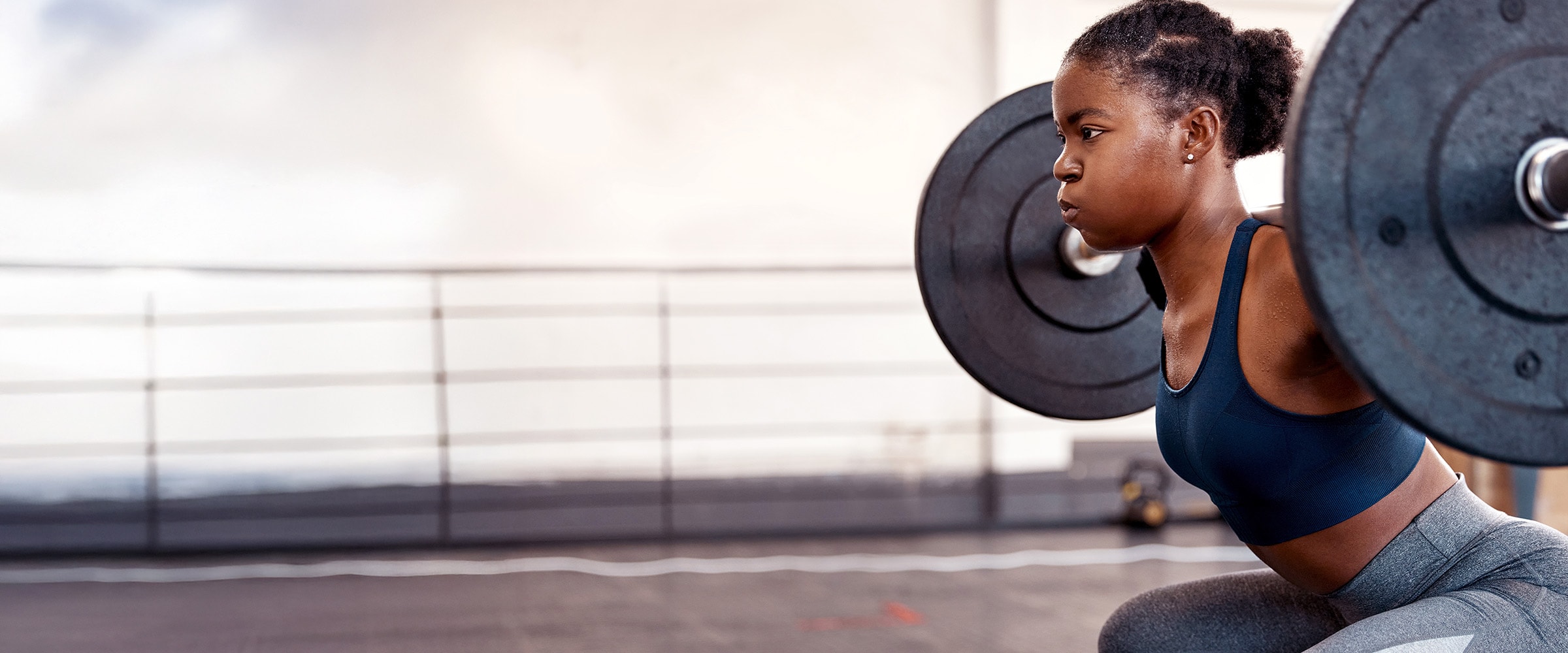 Photo of African-american woman doing barbell squats.
