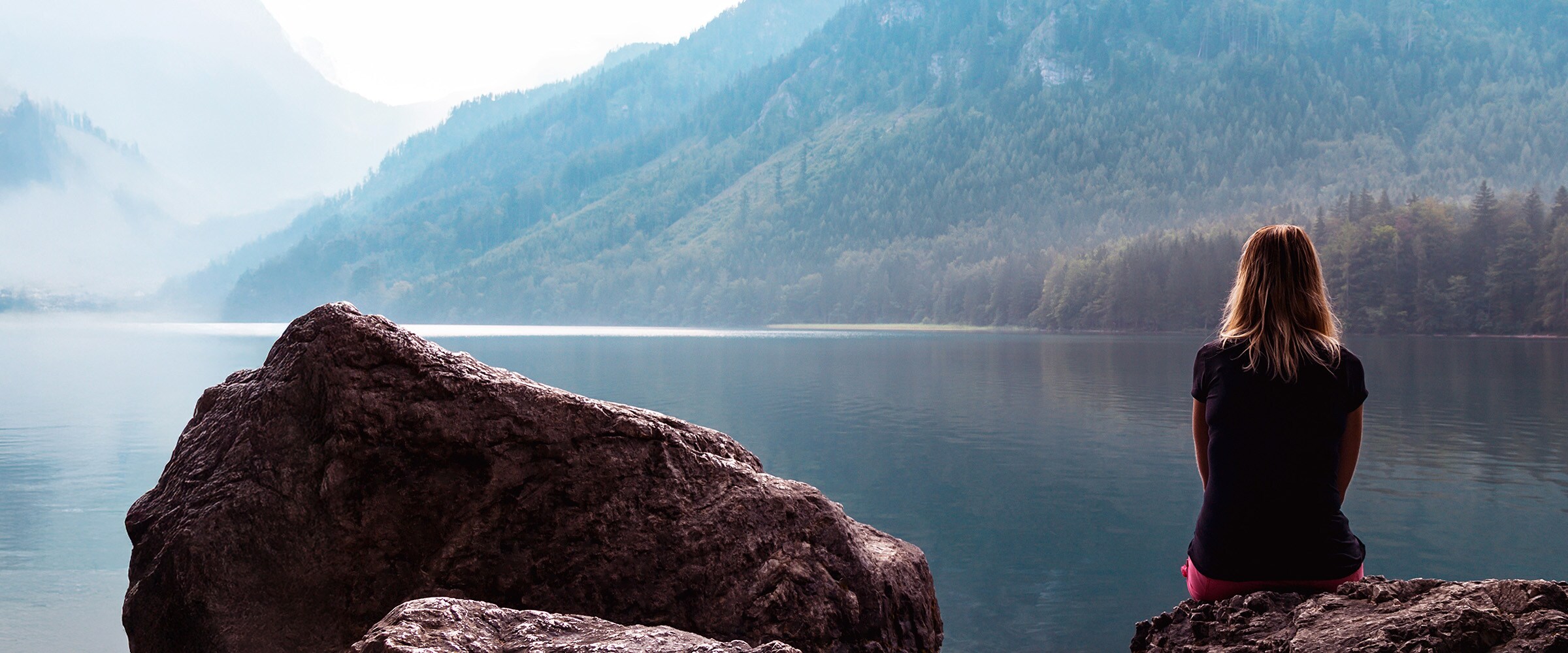 Photo of woman sitting at lake's edge.