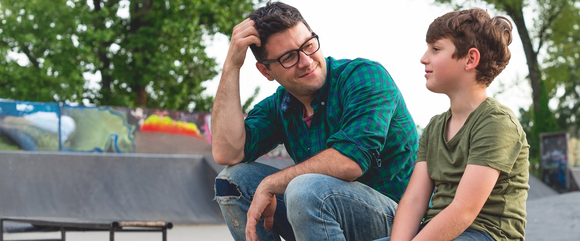 Dad sitting on curb with son having a talk.