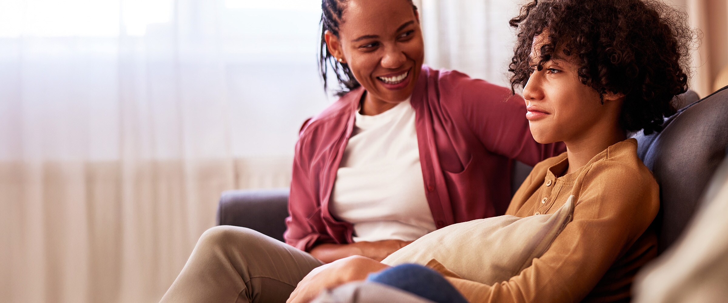 Photo of African American woman talking to son on a couch.