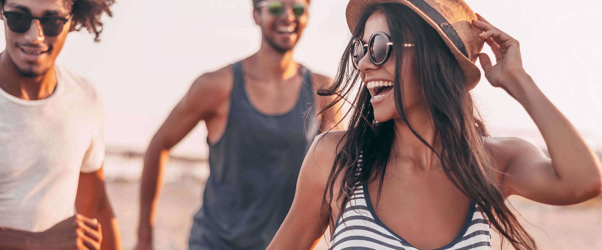 Photo of young adults laughing and playing near a beach.