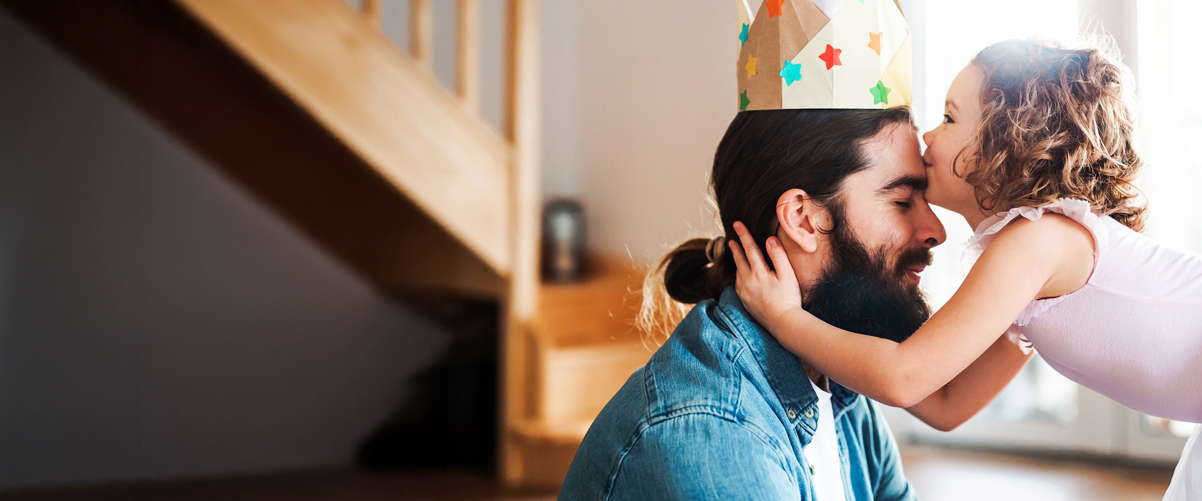 Photo of dad being kissed on the forehead by daughter.