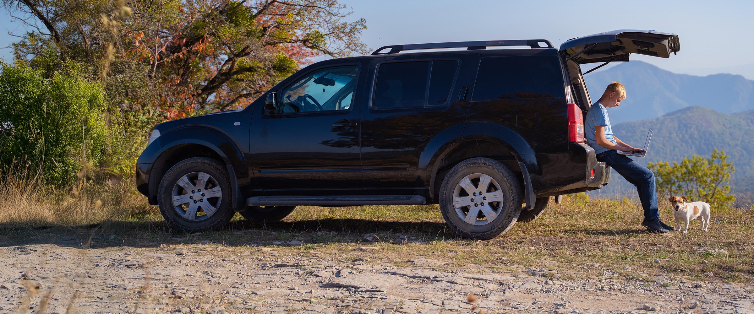 Photo of a man sitting on the back of a SUV.