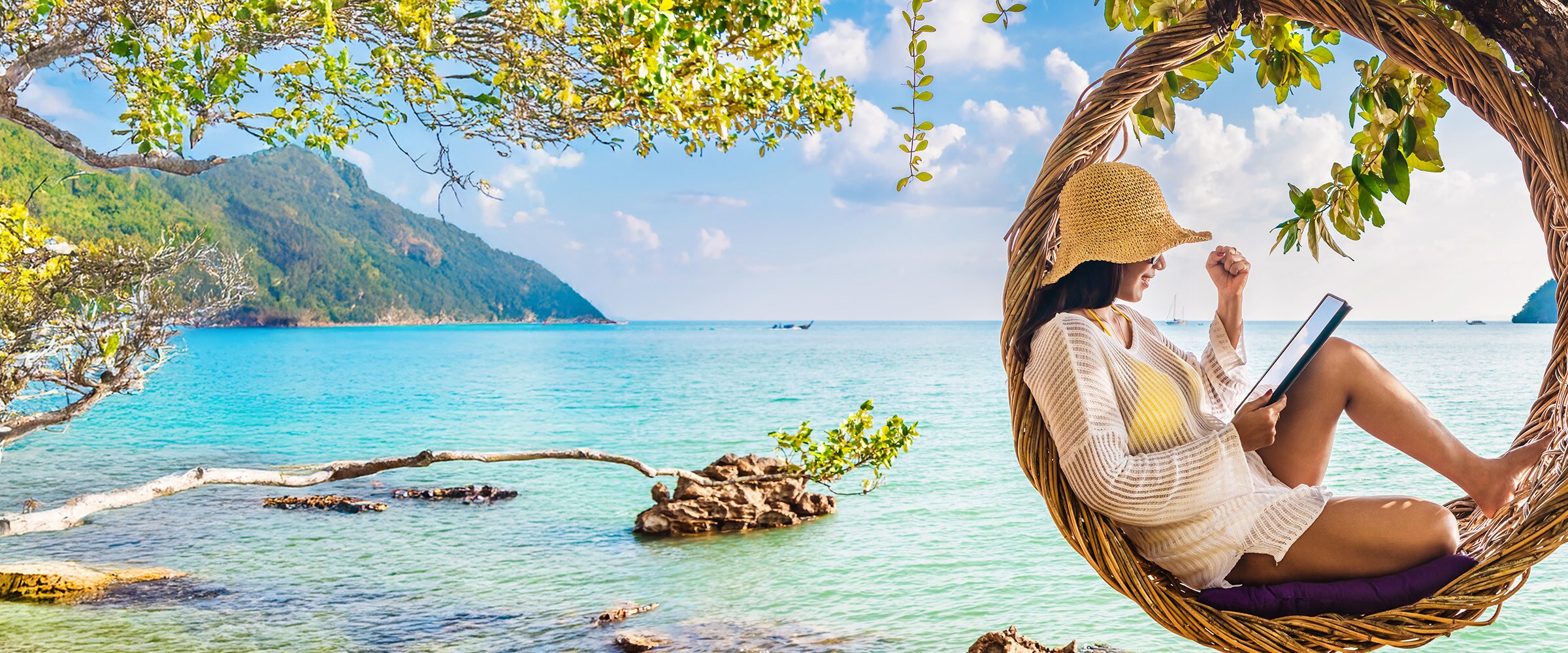 Photo of woman resting in a circular hammock overlooking blue waters.
