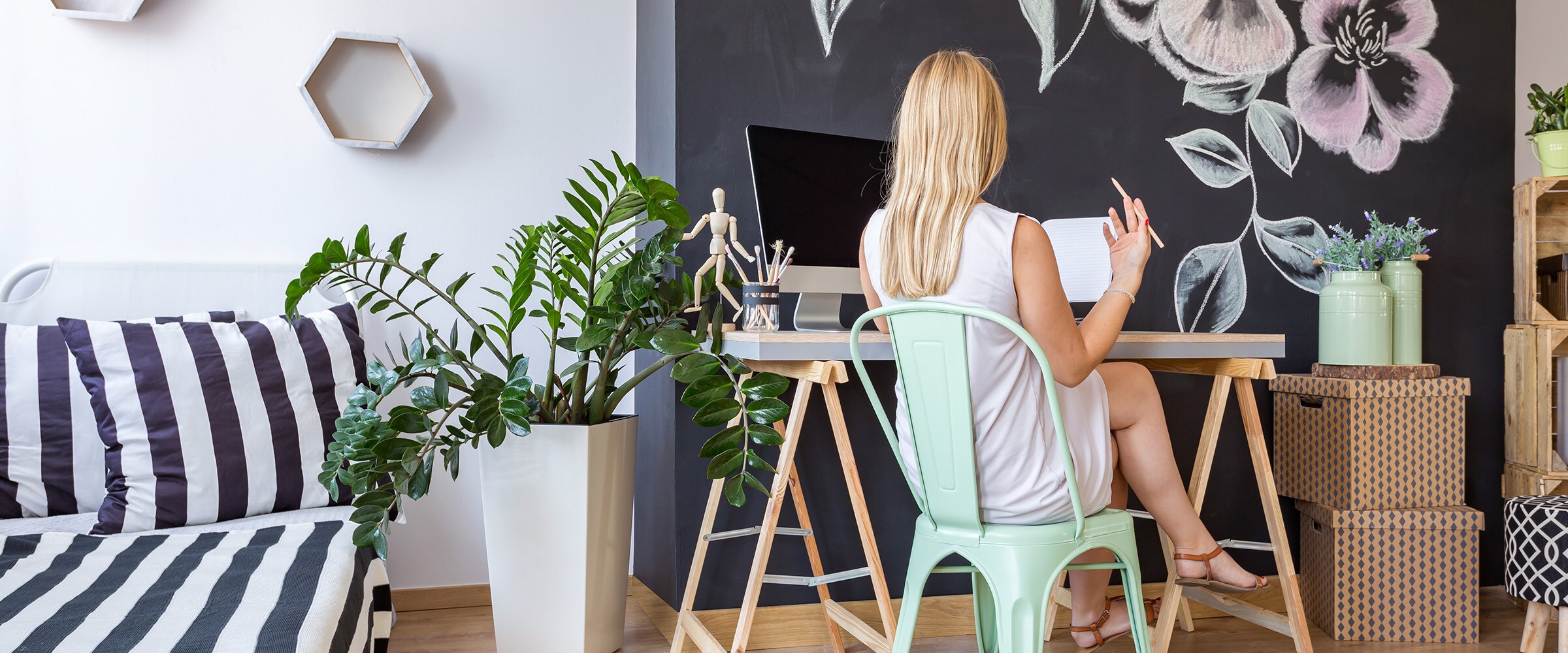 Photo of the back of a woman sitting at a hip home office desk.