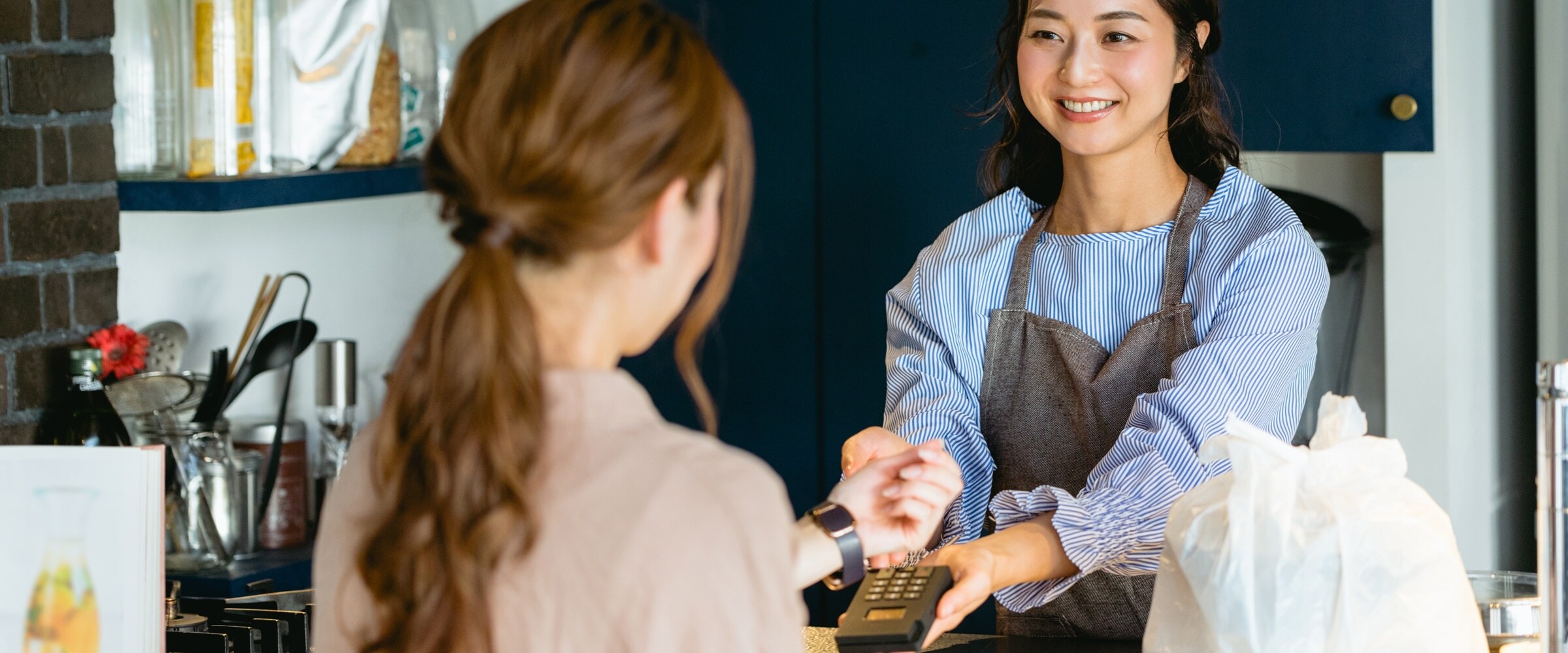 Photo of young woman working as a store clerk helping a customer.