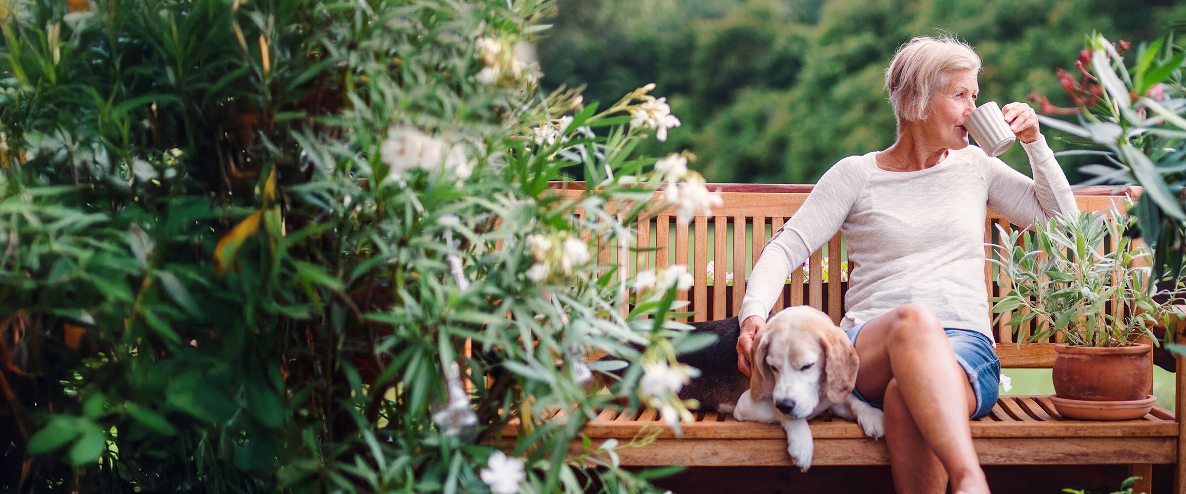 Photo of woman outside a bench, sipping from a cup.