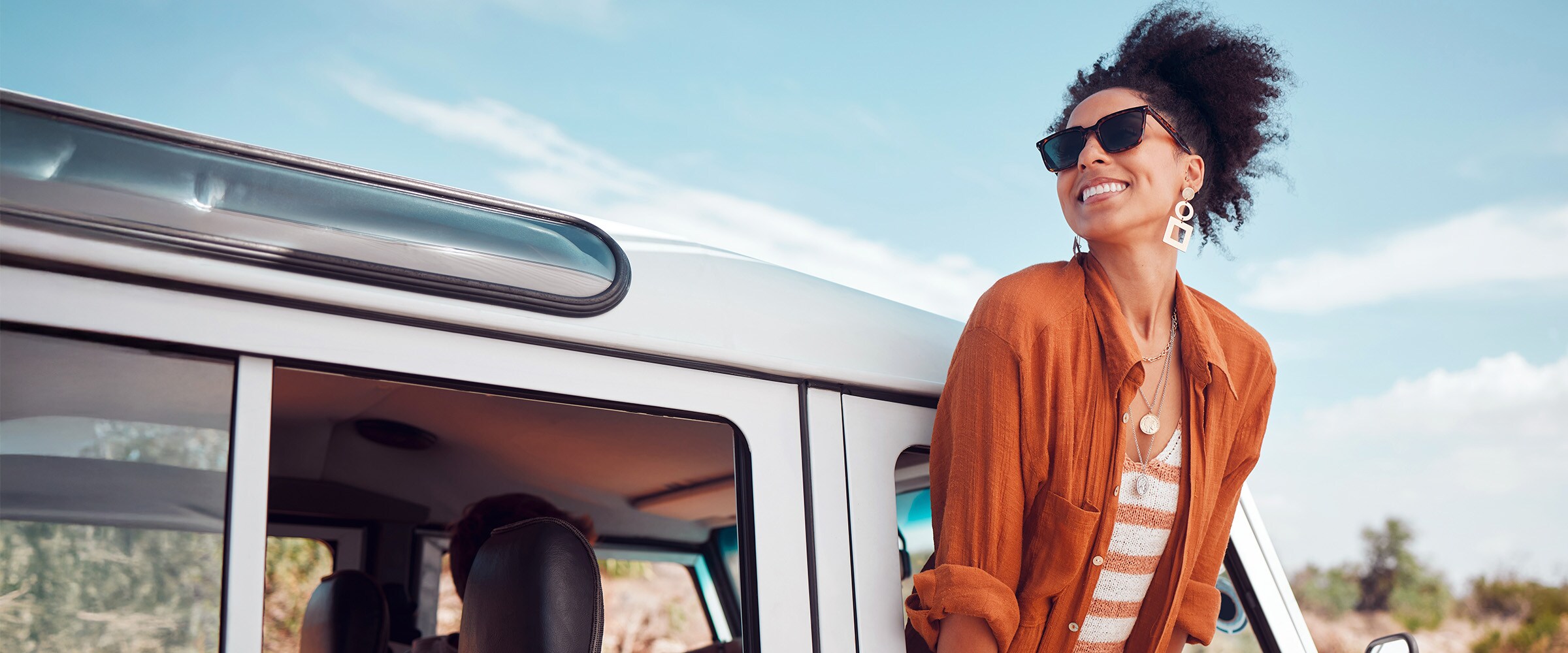 Photo of African American woman with sunglasses leaning out of a car.