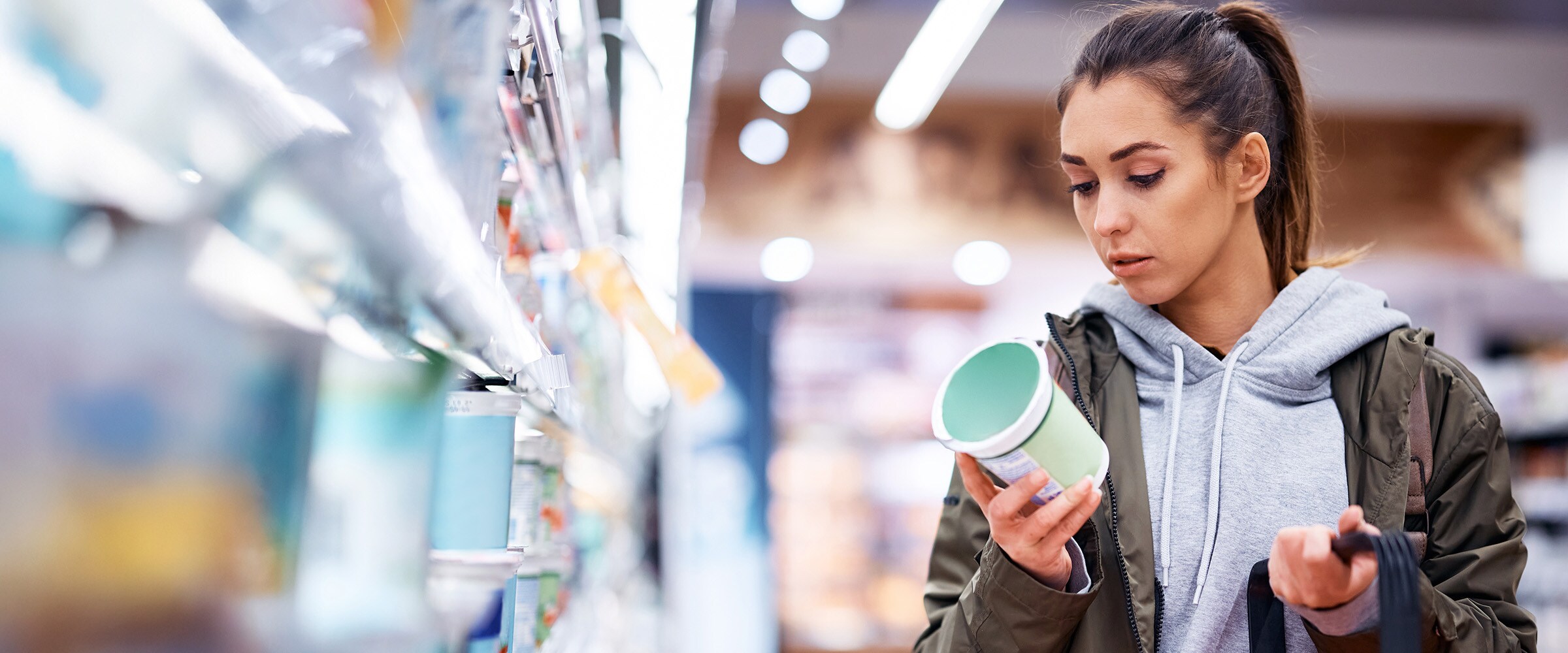Photo of woman scrutinizing the price of a product she is holding.