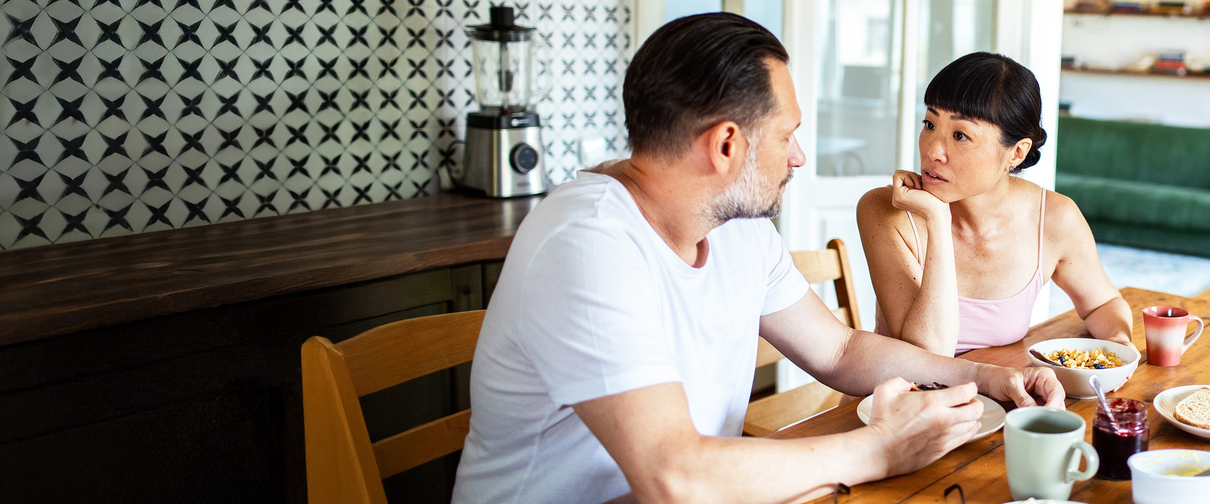 Photo of couple talking to each other at the kitchen table.