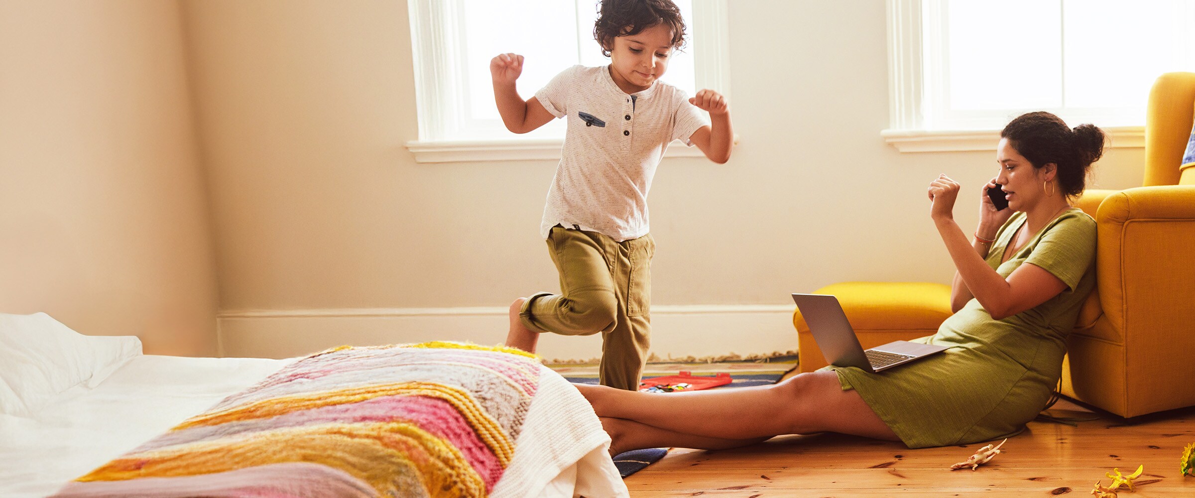 Photo of mom on phone with child running around the room.
