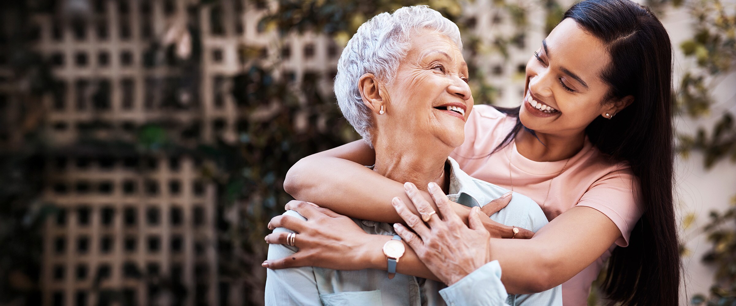 Photo of daughter with arms around elderly older woman.