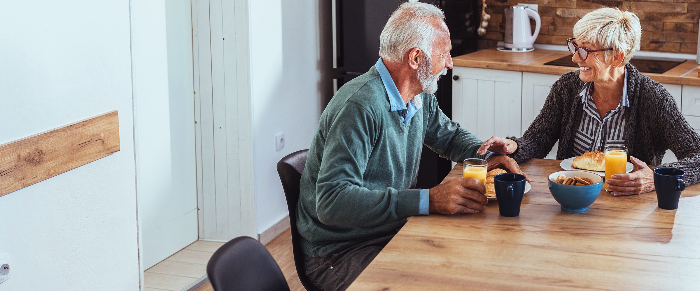 Photo of elderly couple sitting a their breakfast table.