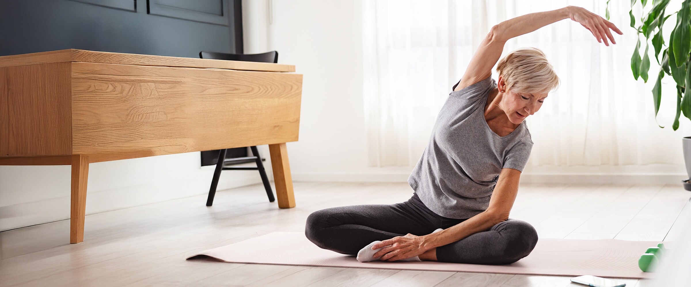 Photo of older woman stretching on the floor of her home.