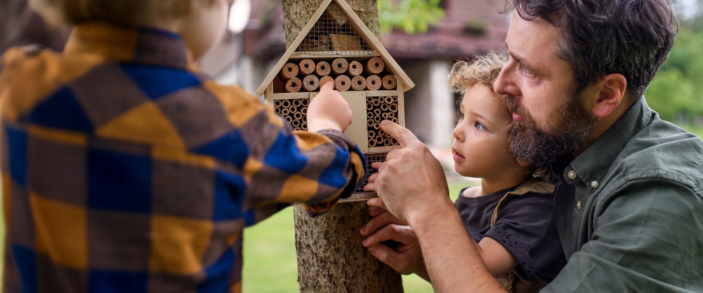 Photo of dad with kids touching a bird house .