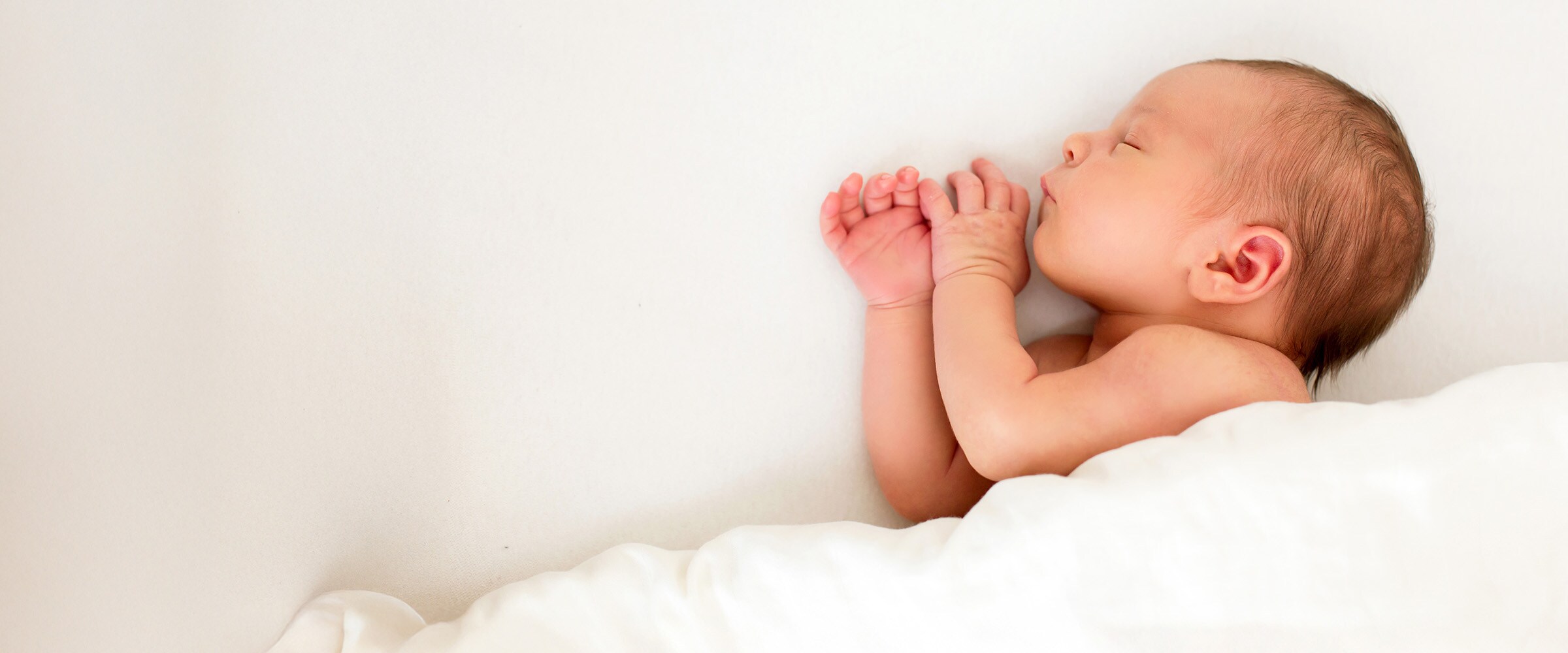 Photo of a newborn wrapped in a while blanket.