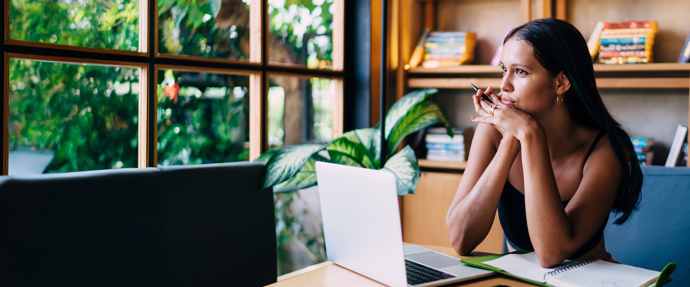 Photo of woman at a desk looking as if she is pondering something.