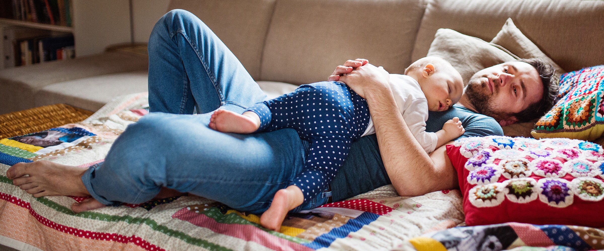 Photo of dad lying on couch with baby resting on his chest.