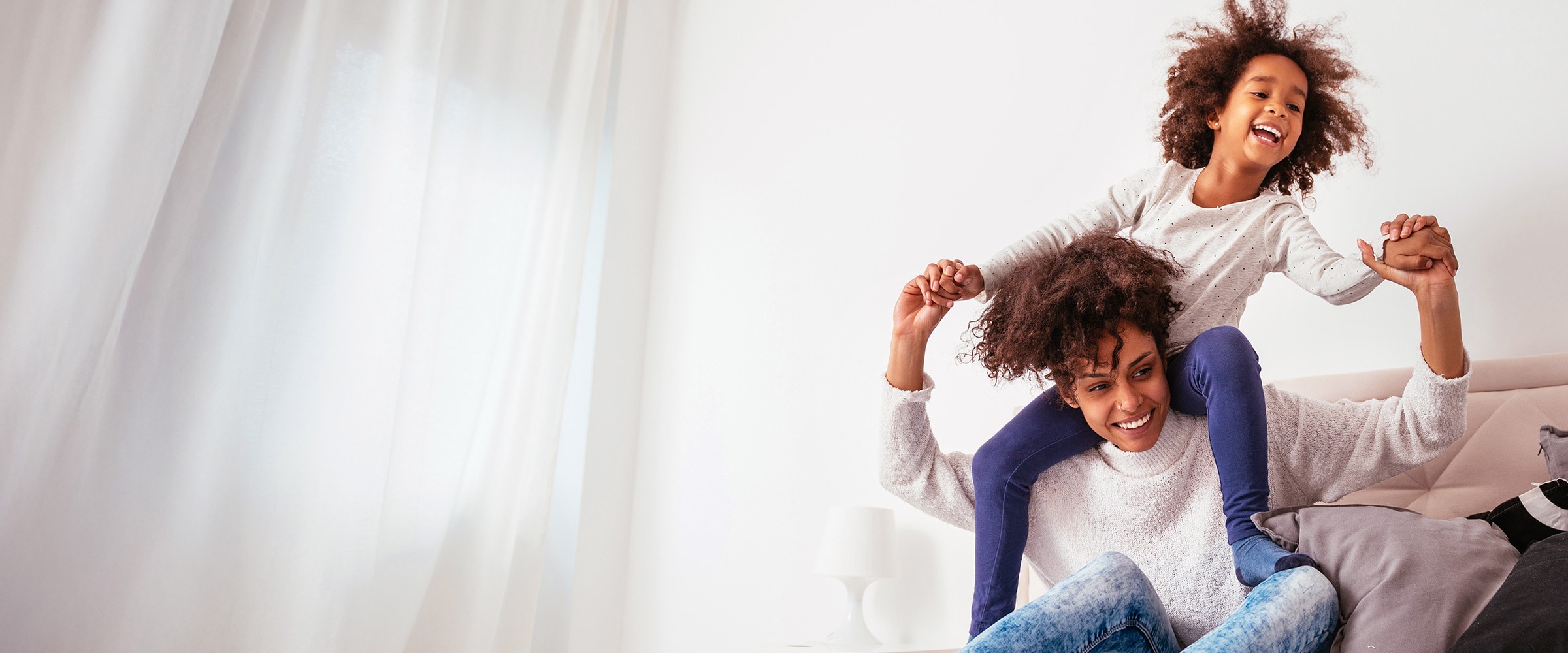Photo of African American mom with young daughter riding on her back.