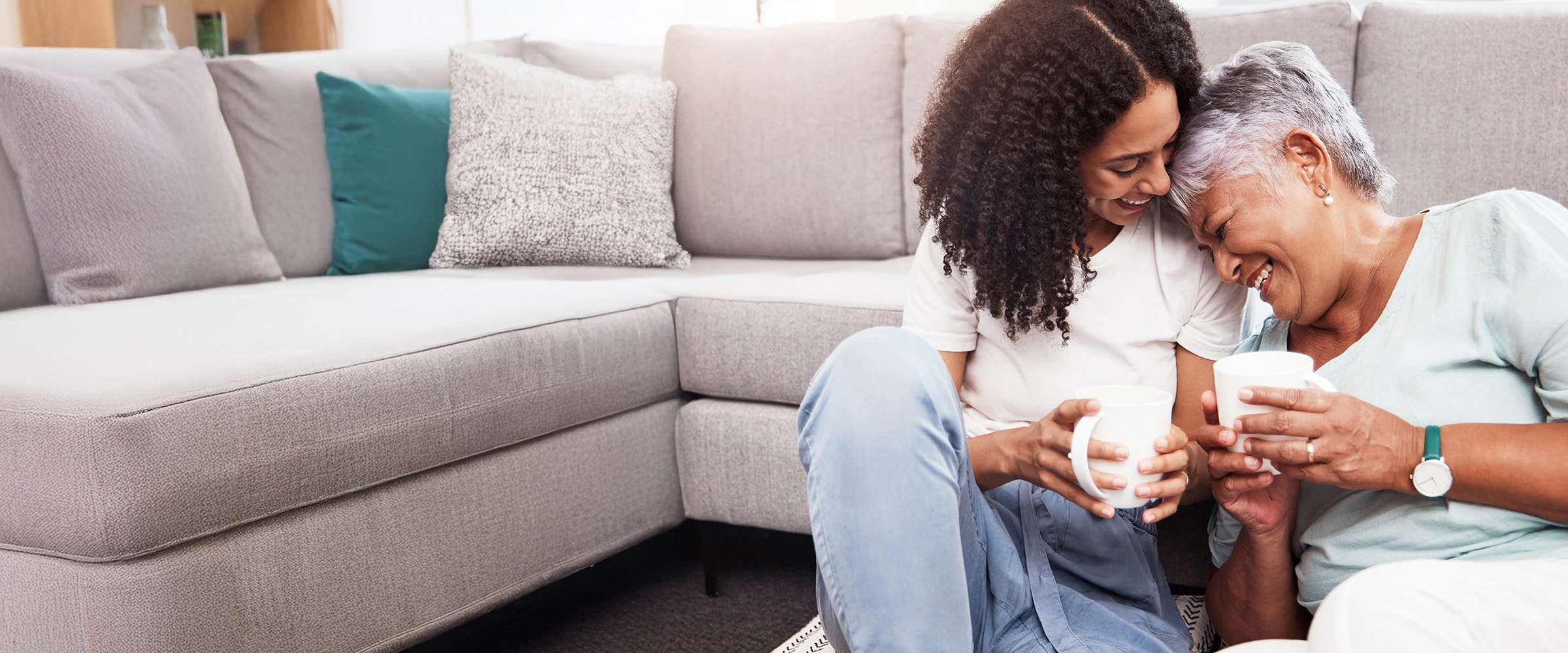 Photo of mother and daughter holding each other close on the floor near a couch.