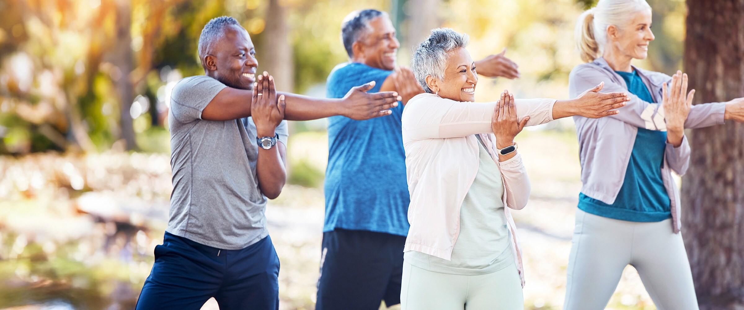 Photo of older people doing stretching exercises outdoors.