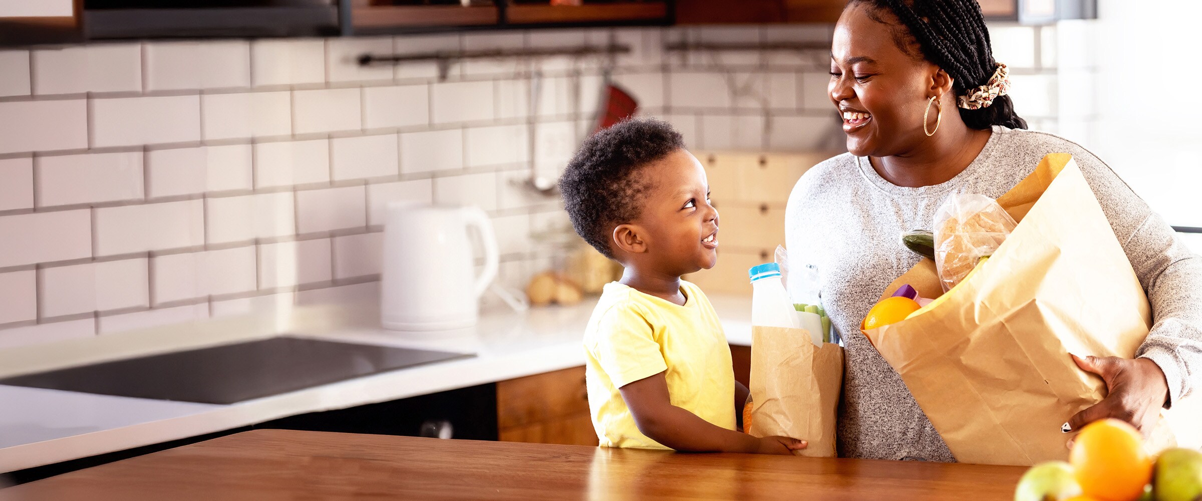 Photo of mother and son setting down groceries on the kitchen counter.